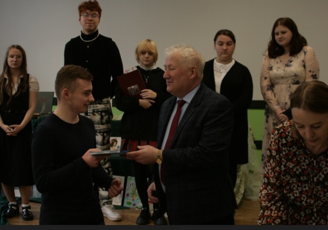 Dyrektor szkoły wręcza nagrodę jednemu z laureatów konkursu recytatorskiego